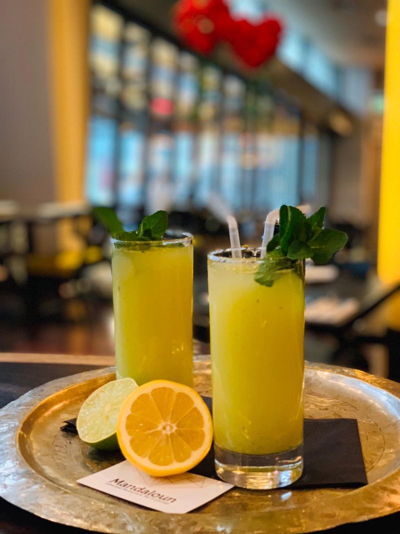 Two tall glasses of fresh juice with mint, served on a brass tray