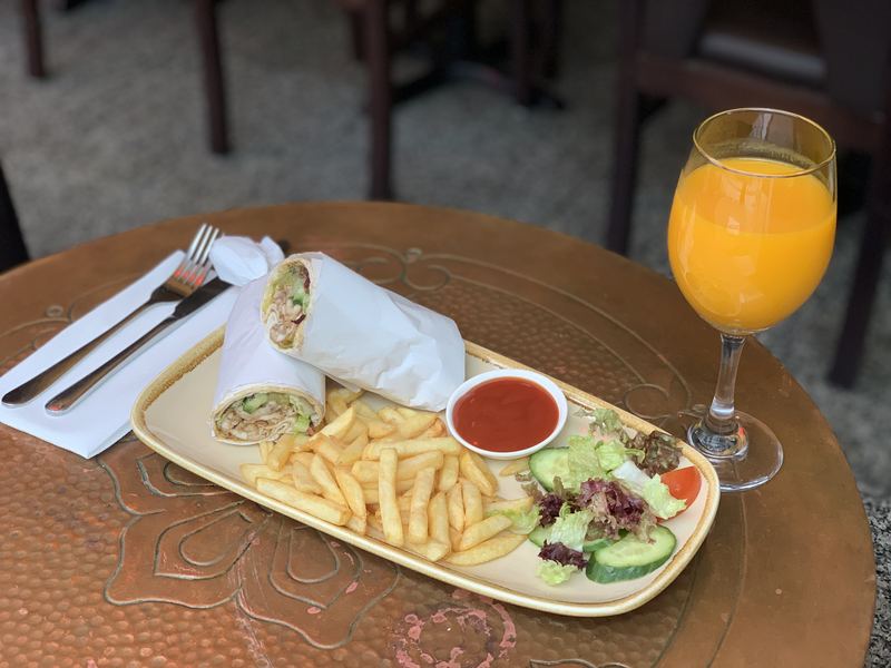 A shawarma wrap with chips, salad and orange juice